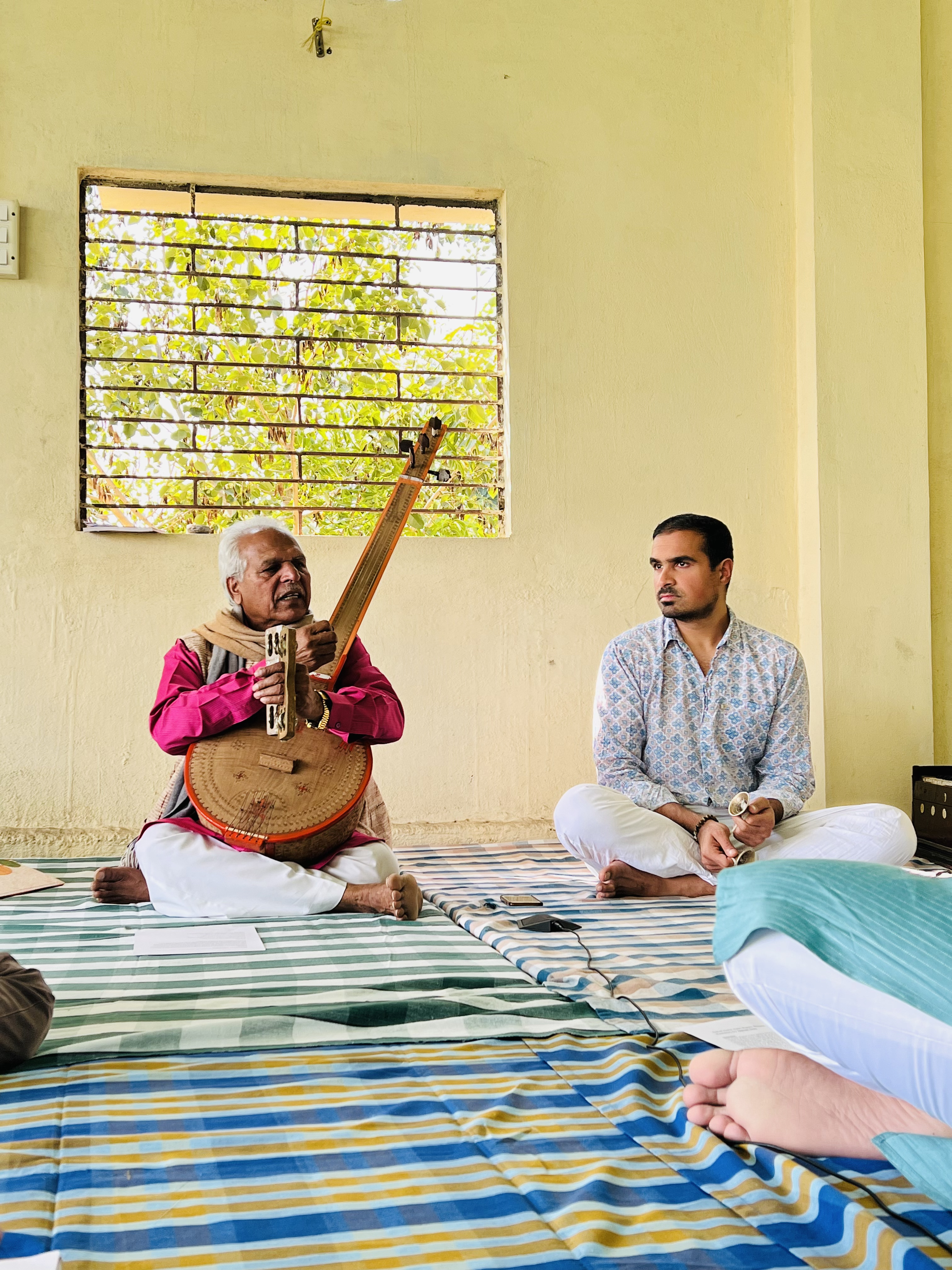 Prahlad Singh Tipaniya singing with a tambura beside Priyal Maheshwari during a Naad Brahma retreat
